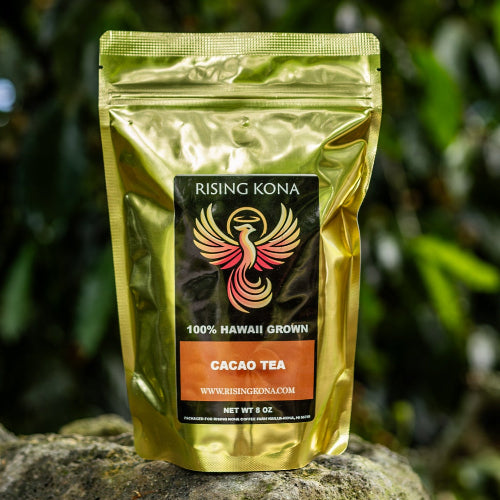 Gold tea package with a logo on a rock in front of green foliage