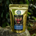 Rising Kona coffee package on a rock with greenery in the background