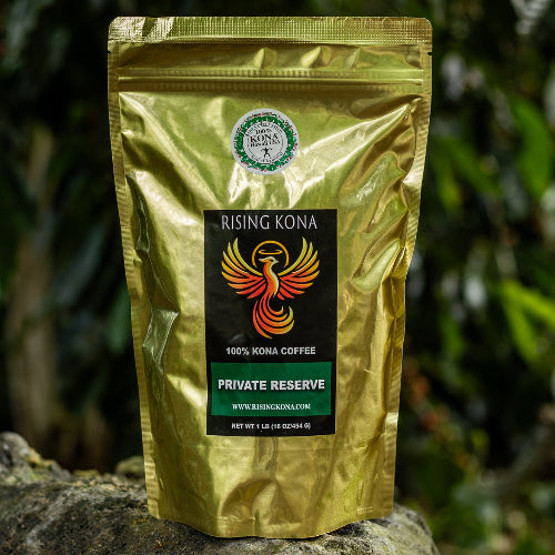 Gold coffee bag with a label on a rock in front of a coffee tree